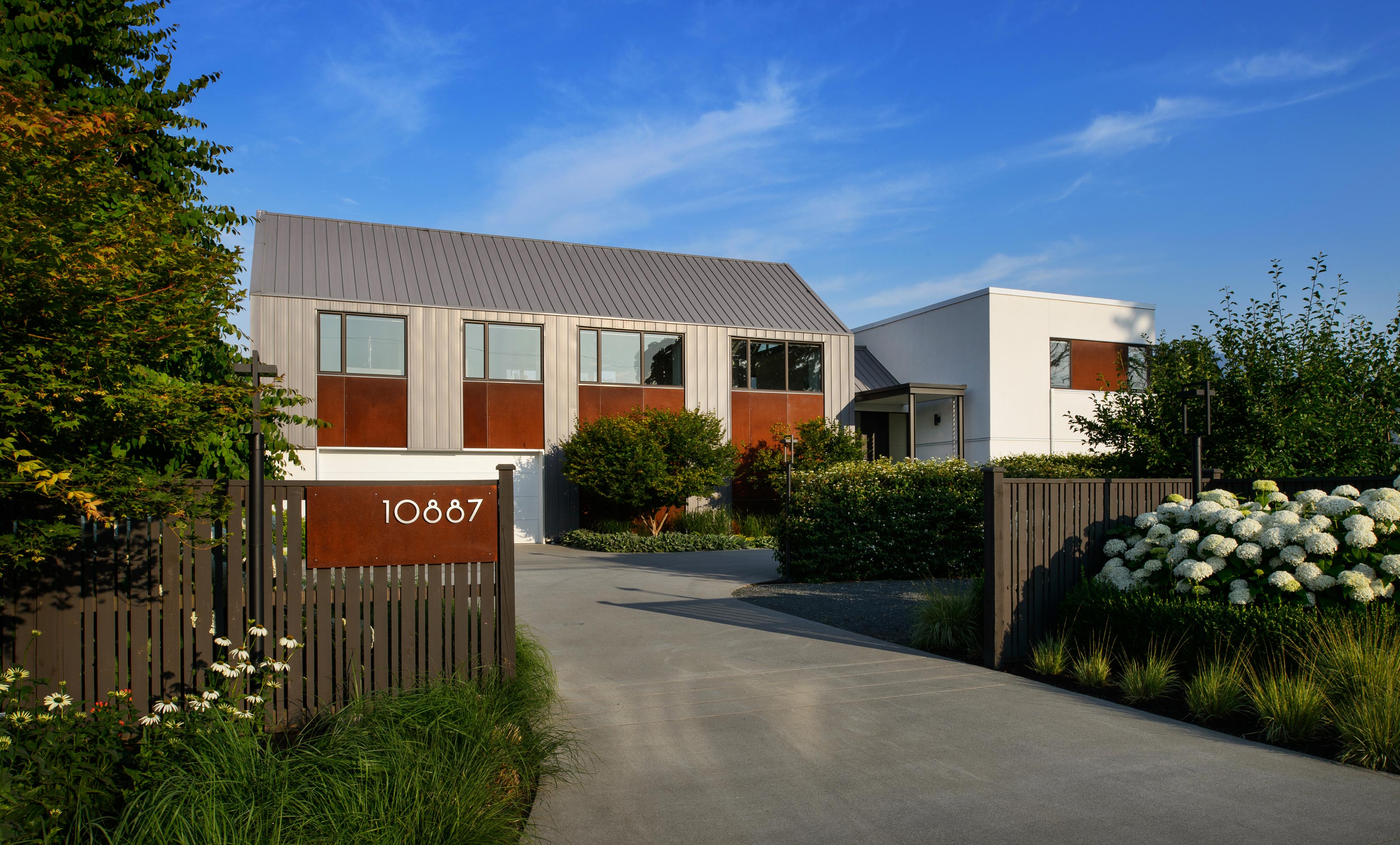 Front view of modern home with landscape of white hydrangeas, echinacea, grasses and shrubs.