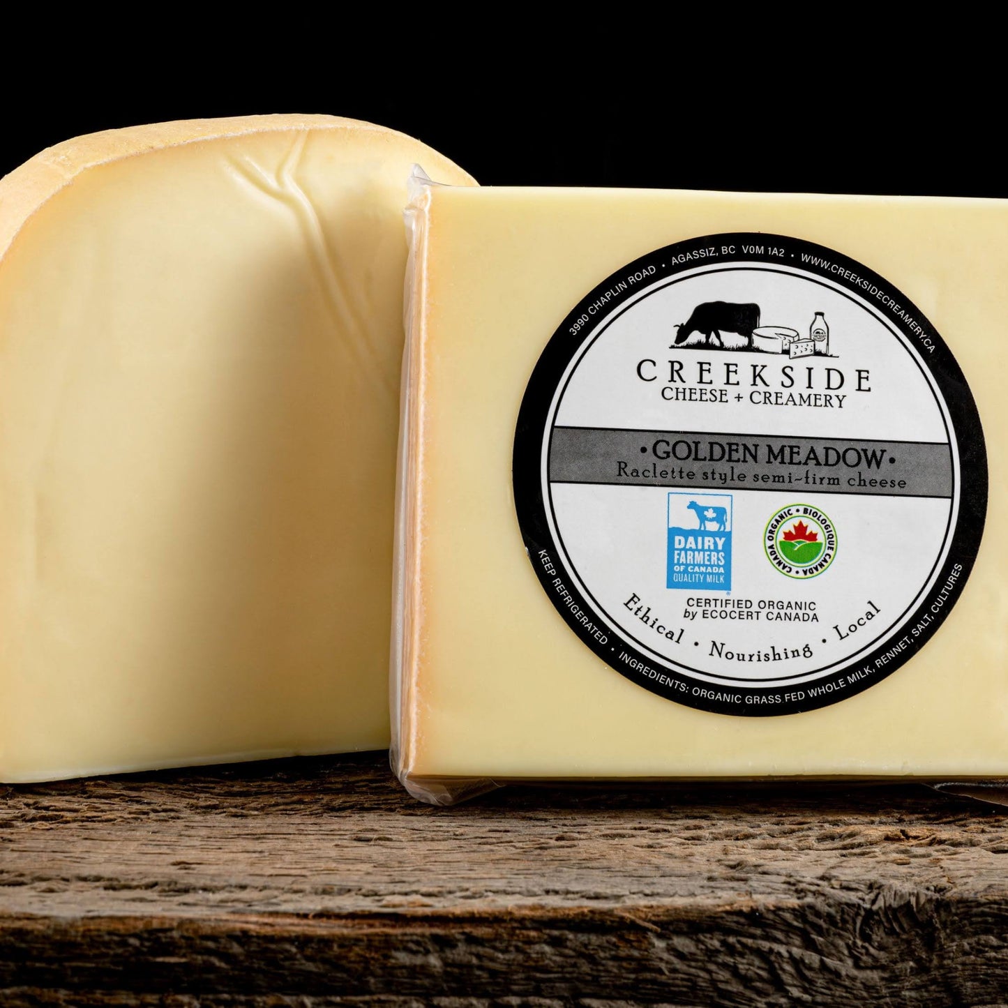 Block of cheese with Creekside Cheese & Creamery label on a wooden surface