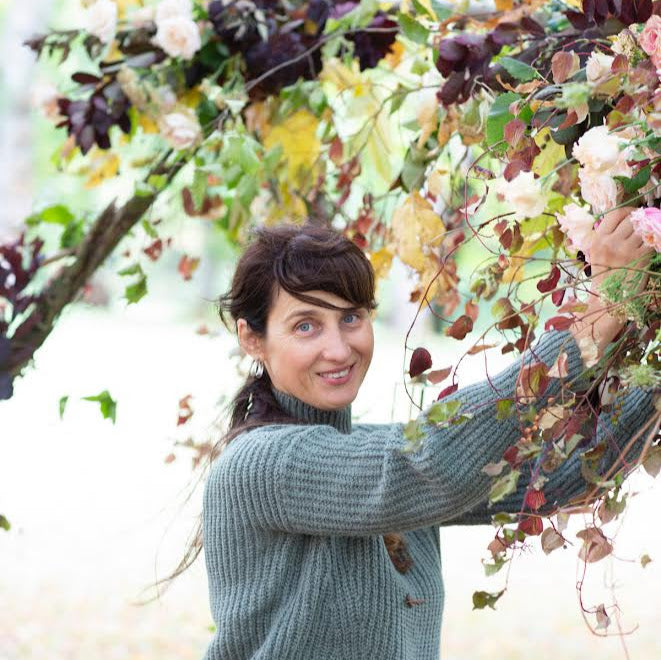 Woman holding a large floral arrangement outdoors