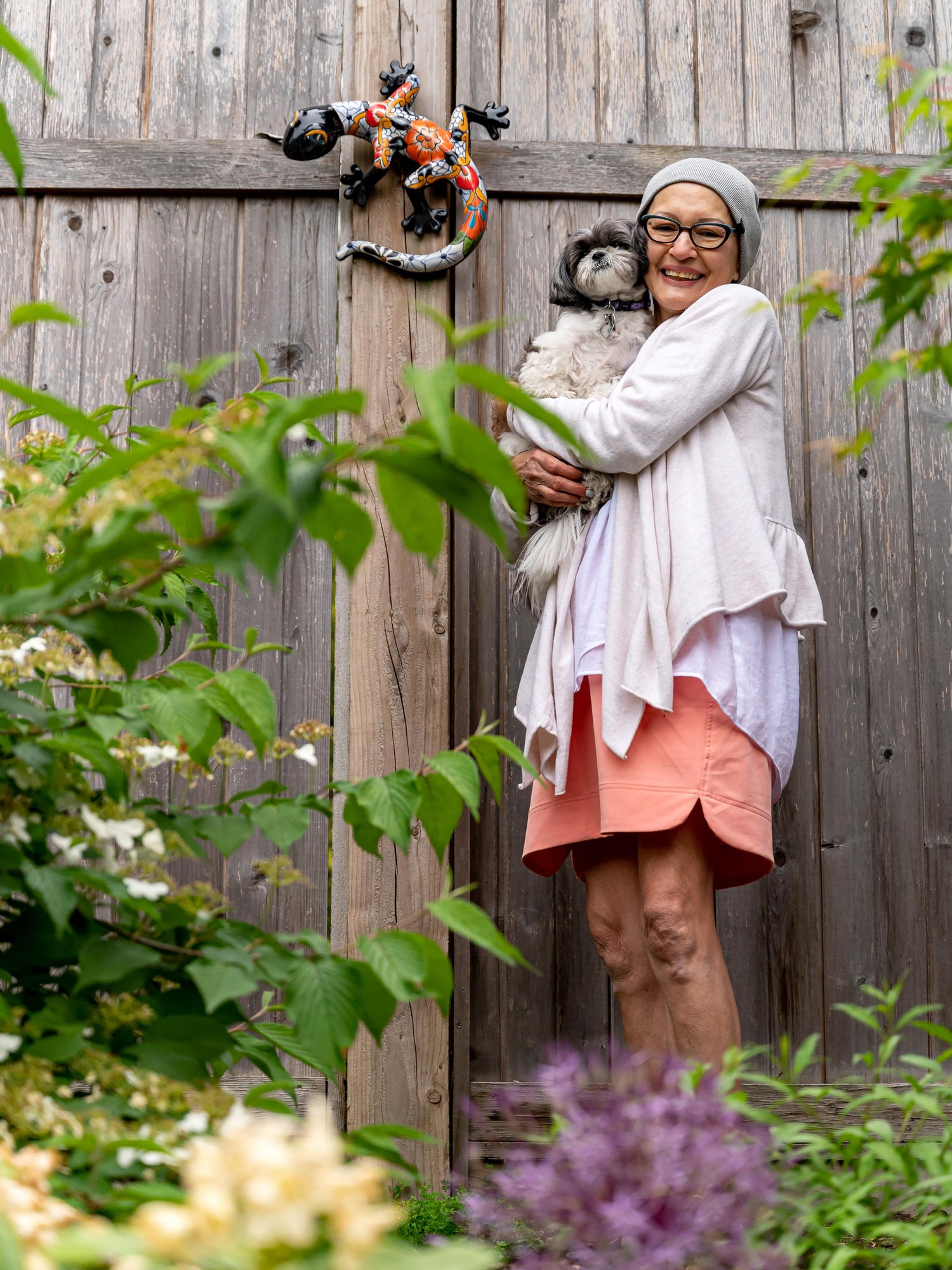 Woman in garden holding her puppy and smiling. 