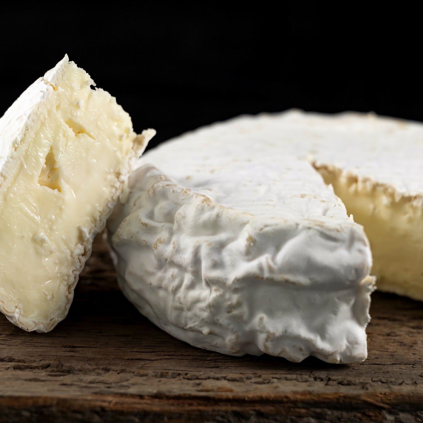 Close-up of soft cheese on a wooden board with a dark background