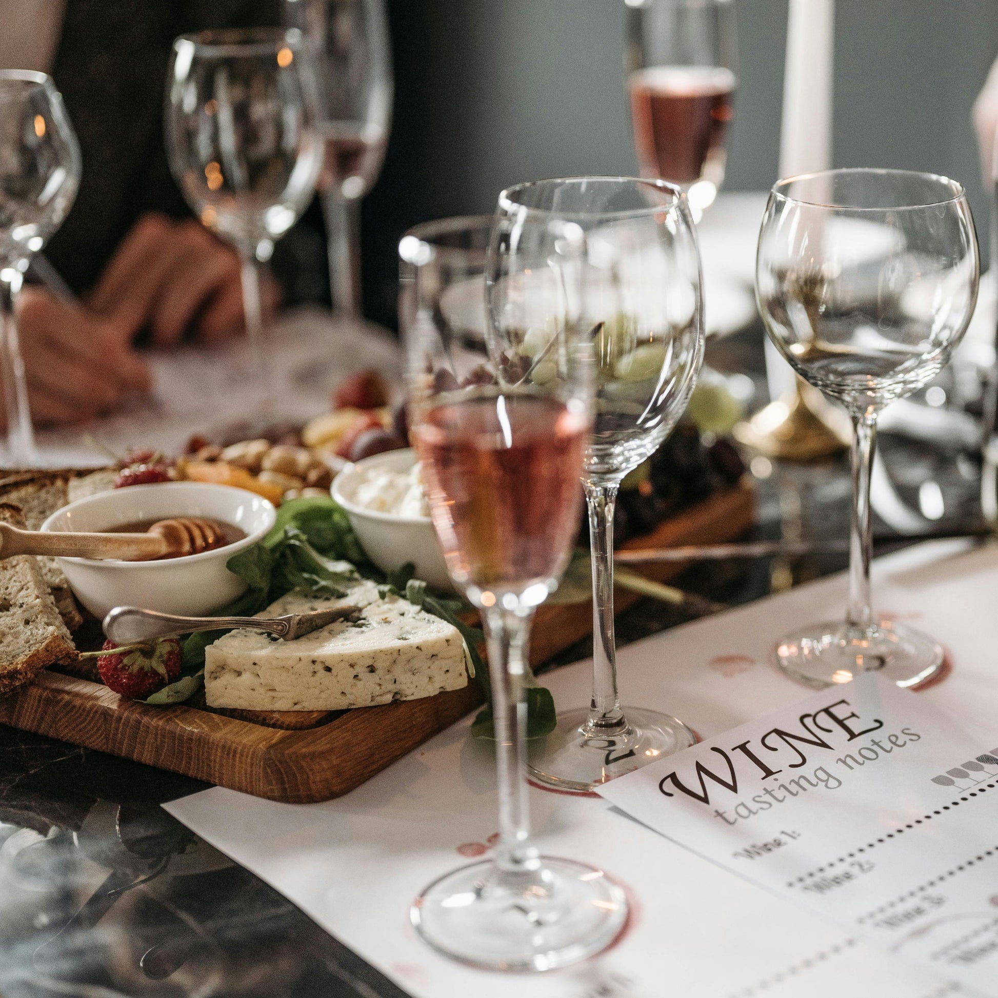 Wine glasses with red wine on a table with food and a wine tasting sheet.