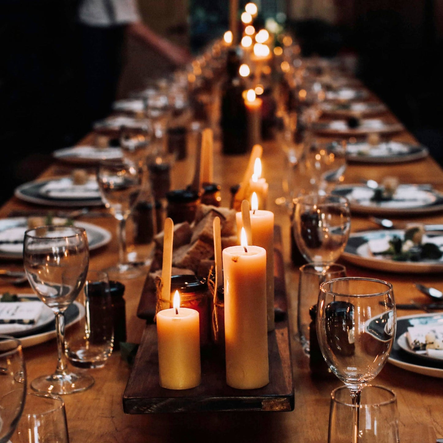 Long dining table set for a meal with candles and glasses.