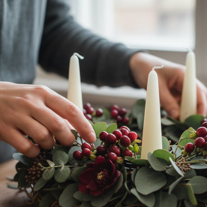 Person arranging candles and flowers on a table