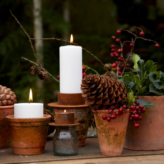 Decorative setup with candles, pinecones, and berries on a wooden surface.